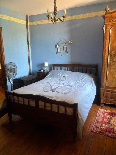 a bedroom with a large bed with white sheets and a fan at Maison de Campagne in Trézelles