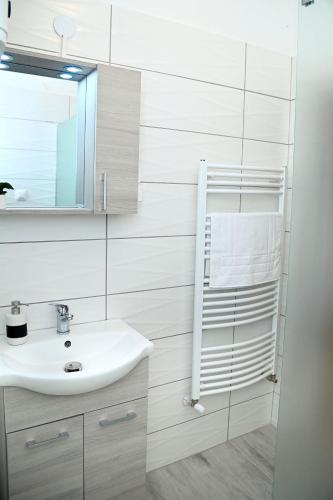 a white bathroom with a sink and a mirror at Rejtekhely Apartman in Miskolc
