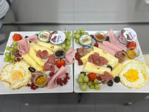 a plate of food with cheese and meats and grapes at Hotel &Restaurant Meteora in Glauchau