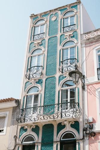 a tall green and white building with windows and balconies at Good Old Days - Guesthouse in Caldas da Rainha