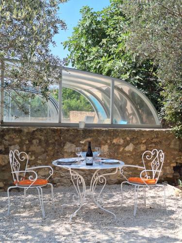 a table and two chairs with a bottle of wine at Gîte avec piscine couverte in Saint-Julien-de-Peyrolas