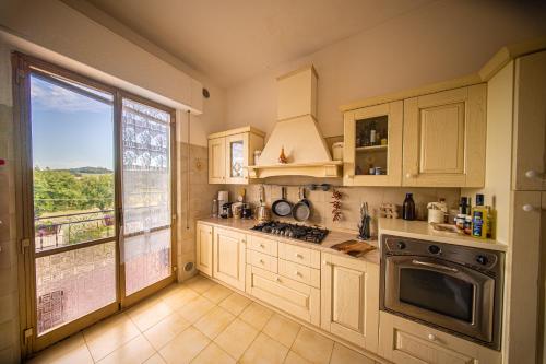 a kitchen with white cabinets and a large window at Cozy Room with Balcony, Ping Pong & Billiard Table in Monte Molino