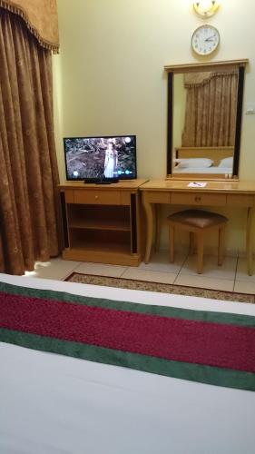 a living room with a tv and a desk with a mirror at Muscat International Hotel in Muscat