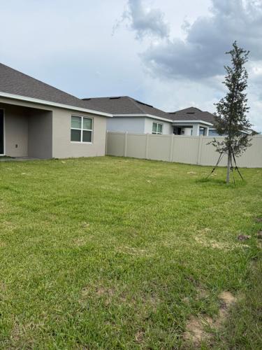 a house with a fence and a tree in a yard at Modern Lux 3BR Home Near Disney and Lego Land! in Haines City