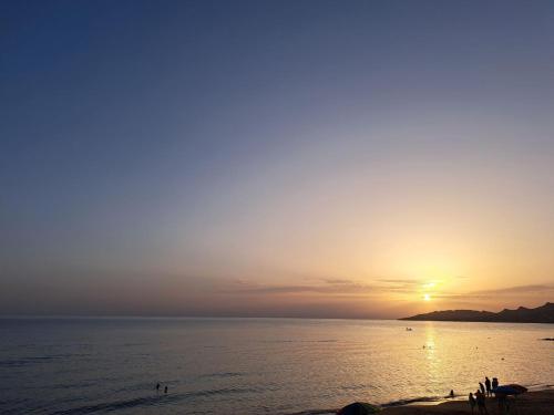 a sunset over the ocean with people on the beach at Appartamento Castel Sant'Angelo in Licata