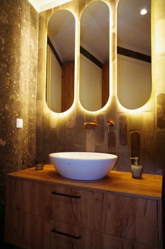 a bathroom with a white sink and three mirrors at Absolute Athens Acropolis Muses in Athens