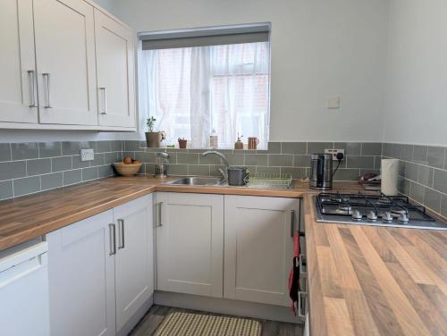 a kitchen with white cabinets and a sink and a window at Stylish 2 Bedroom Apartment in Belvedere