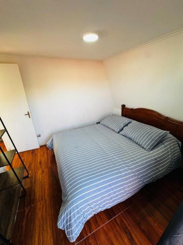 a bedroom with a bed with a blue striped comforter at Lindo Departamento Con Terraza y Parrilla in Concón