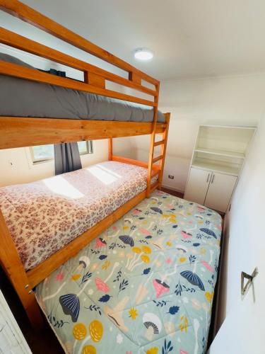 a bunk bed in a small room with a bedsheet at Lindo Departamento Con Terraza y Parrilla in Concón
