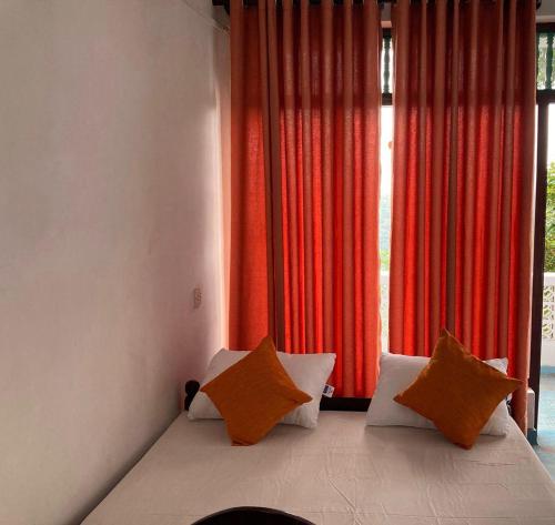 a bedroom with a bed with orange and white pillows at Ameeila Villa in Kandy
