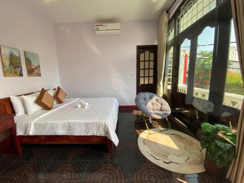 a bedroom with a bed and a chair and a window at Lavande Hue Homestay in Hue