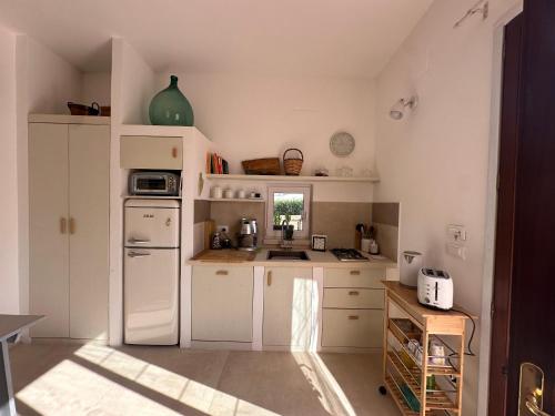 a kitchen with white cabinets and a white refrigerator at La casa nel verde klimt in Supersano