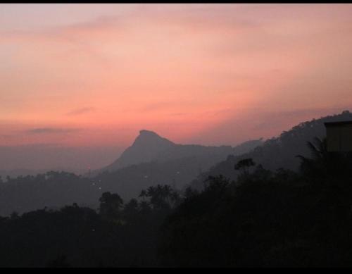 a sunset with a mountain in the background at Asprin Homestay in Munnar