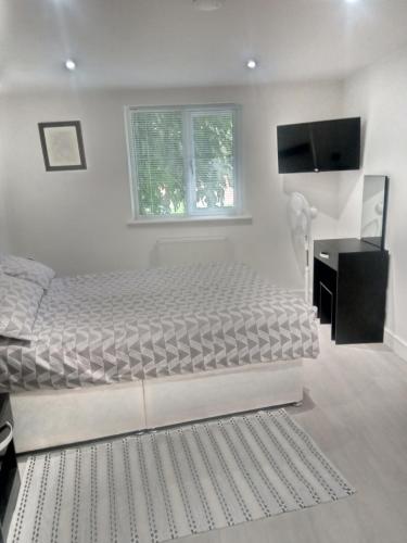 ein weißes Schlafzimmer mit einem Bett und einem Fernseher in der Unterkunft The Stage Door in Slough