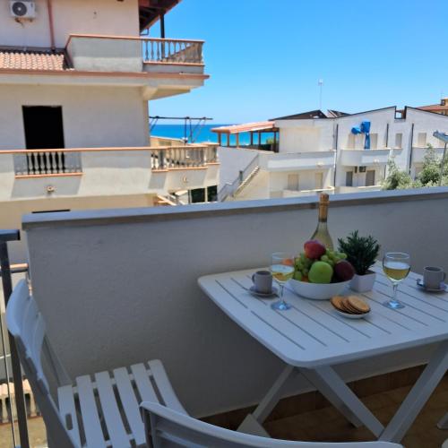 a table with a bowl of fruit and a bottle of wine at Bella Italia in Marina di Strongoli