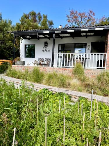 a white house with two benches in front of it at Salt & Pepper in Mossel Bay