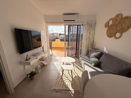 a living room with a gray couch and a television at Sunny Apartment Loma de Arguineguín in Arguineguín