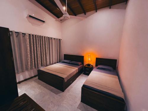 a bedroom with two beds and a lamp in it at Windgate Estate Bungalow Galaha in Palle Deltota