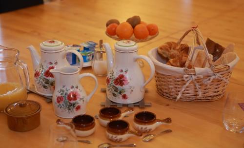 a table with three tea pots and a basket of fruit at les Tours de Bombel in Saint-Amand-de-Coly