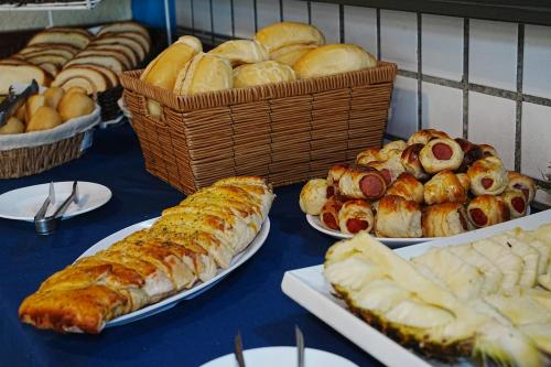 a table topped with plates of bread and pastries at Hotel Pousada Vivendas do Sol e Mar in Caraguatatuba