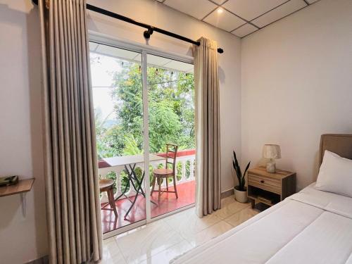 a bedroom with a bed and a window with a balcony at Kandy View Stay in Kandy