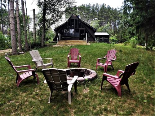 a group of chairs around a fire pit in the grass at The River Cabin in Mauston
