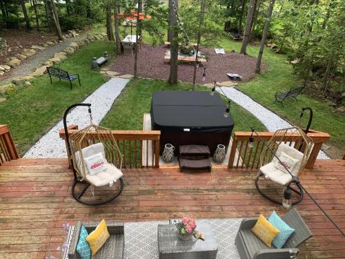 a grill sitting on a wooden deck with two chairs at Majestic Lake Front Chalet in Tobyhanna