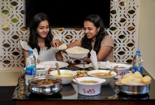 two women sitting at a table with food at Alice Lake Promise in Alleppey