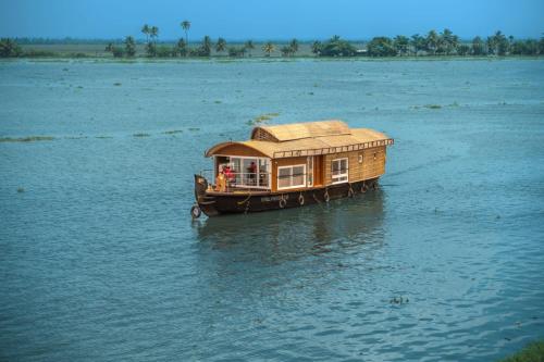 a small boat with a roof on the water at Alice Lake Promise in Alleppey