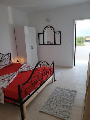 a bedroom with a bed with a red comforter at villa houch serine in Guellala