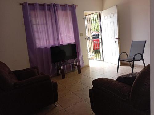 a living room with purple curtains and a tv at Entire house near the city of David in Los Algarrobos