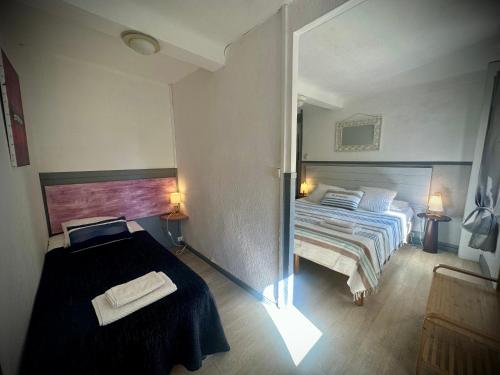 a bedroom with two beds and a mirror at Hôtel Auberge Provençale in Saint-Raphaël