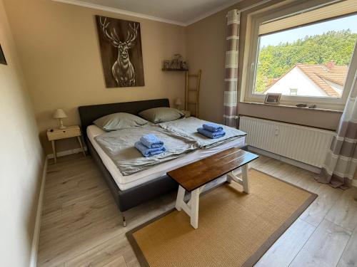 a bedroom with a bed with a table and a window at Ferienwohnung Harzwiese in Bad Sachsa
