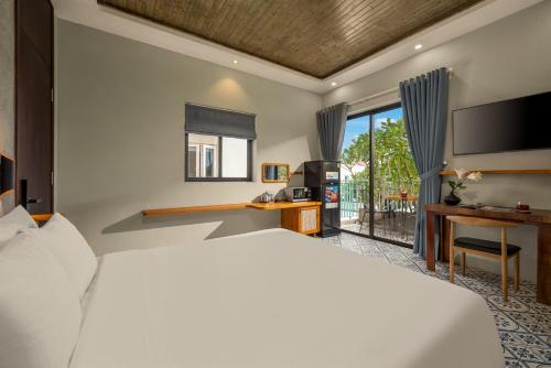 a bedroom with a bed and a desk and a tv at Tropical An Bang Beach Villa in Hoi An