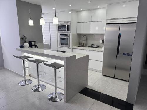 a kitchen with a counter with stools and a refrigerator at Hermoso Apartamento Mañongo - Hasta 6 personas in Naguanagua