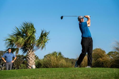 two men playing golf on a golf course at Distinctive Island Living - 835 Bonito Rd, Fripp Island in Fripp Island