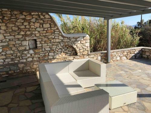 a white bench on a patio with a stone wall at Sunset Paros Antiparos treasure house, Pounta port in Kampos Paros