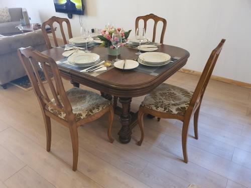 a wooden table with chairs and plates and flowers on it at Gite Sérénité in Magnac-Laval