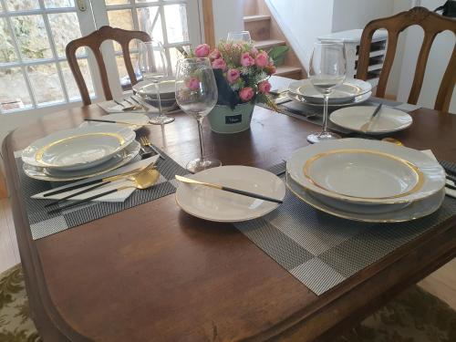 a wooden table with plates and wine glasses on it at Gite Sérénité in Magnac-Laval