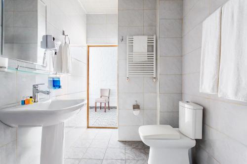 a white bathroom with a toilet and a sink at Solief Hotel in Katartal