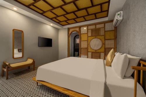 a bedroom with a large white bed and a chair at Tropical An Bang Beach Villa in Hoi An