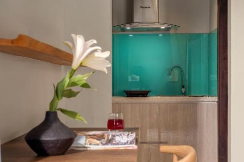 a flower in a vase on a table with a glass at Tropical An Bang Beach Villa in Hoi An