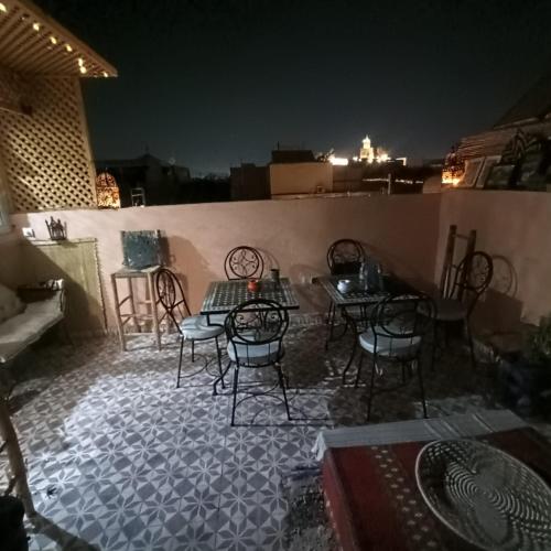 un patio con tavoli e sedie su un tetto notturno di Dar Bellaji l Bed & Breakfast in Medina l Rooftop Koutoubia a Marrakech
