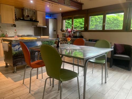 une cuisine avec une table et des chaises en verre dans l'établissement le loft de l'Atelier, à Nans-sous-Sainte-Anne