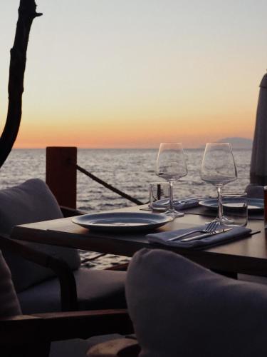 a table with two wine glasses on top of the ocean at Hotel Porta Ksamil in Ksamil