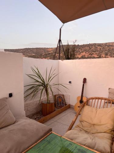 a room with a couch and a guitar on a balcony at Azul Berg Hostel in Tamraght Ouzdar
