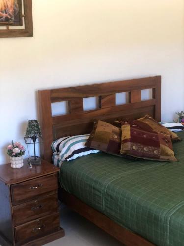 a bedroom with a bed with a wooden headboard and a table at El Rincón de Nukuri by Looking Samaipata in Samaipata