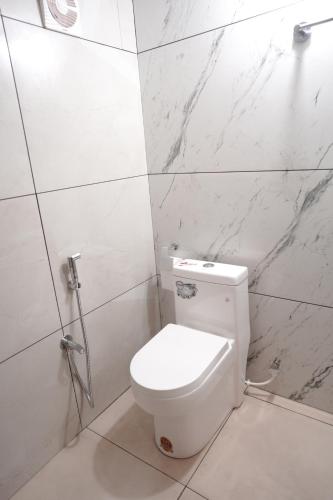 ein weißes WC im Bad mit Marmorwänden in der Unterkunft The Beach Hive in Kappil