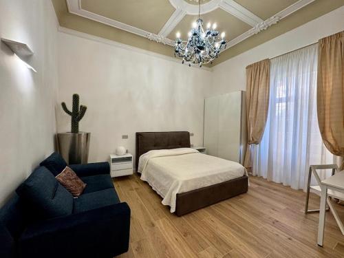 a bedroom with a bed and a couch and a chandelier at Le suite del Duomo - 2 in Cava deʼ Tirreni
