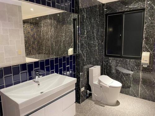 a bathroom with a sink and a toilet and a mirror at Langkei Motel in Daxi